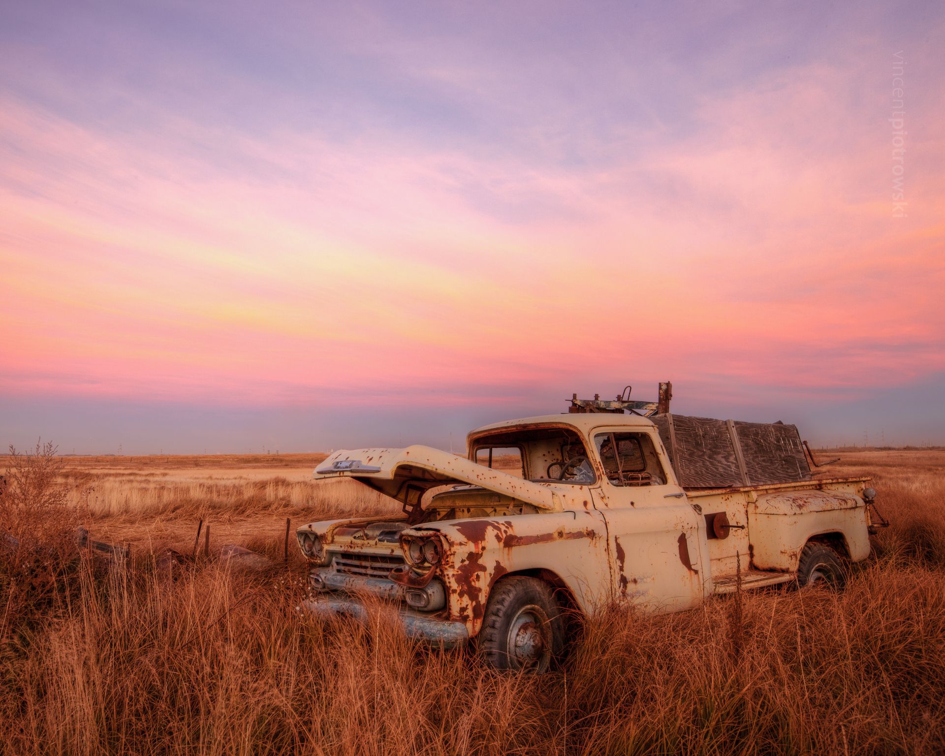 An old beat up 59 chevy truck in a field at sunset