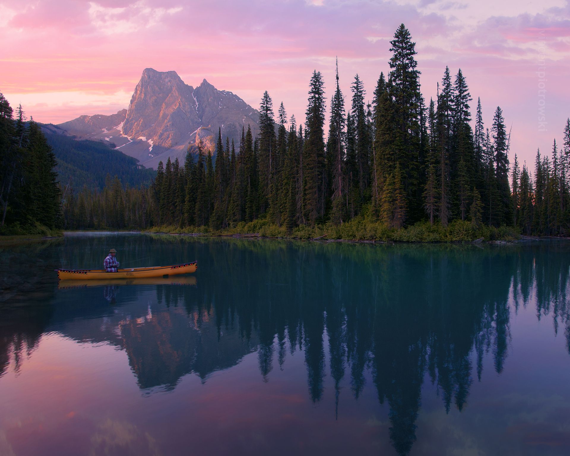 A man fishing out of a kayak on Emerald Lake at sunrise