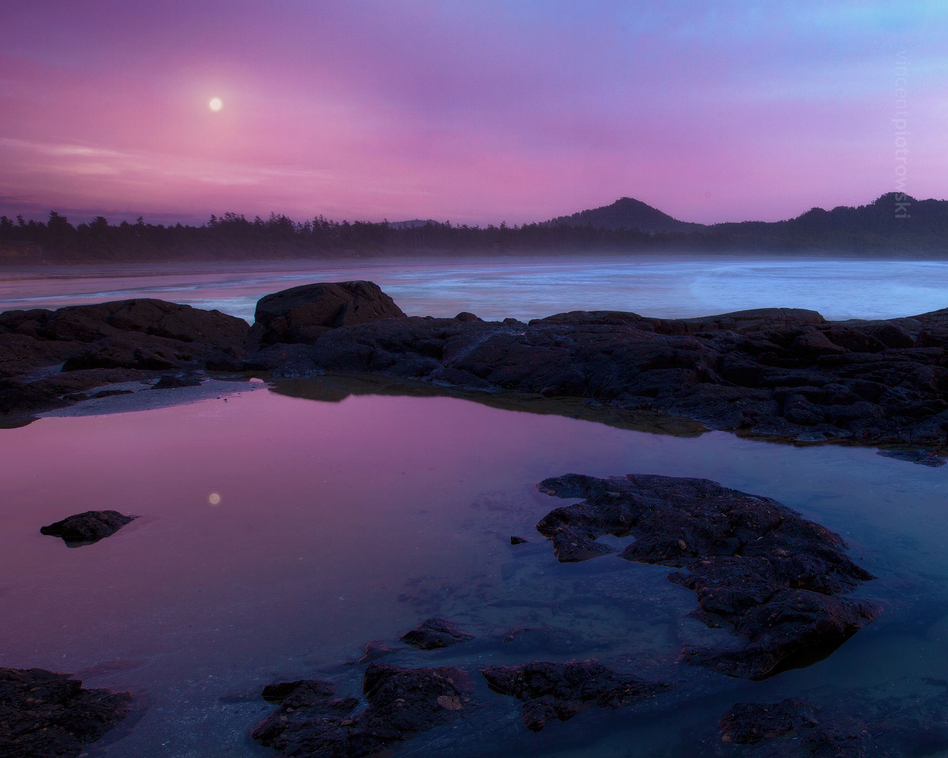 A full moon reflected over a still tide pool taken near Tofino BC