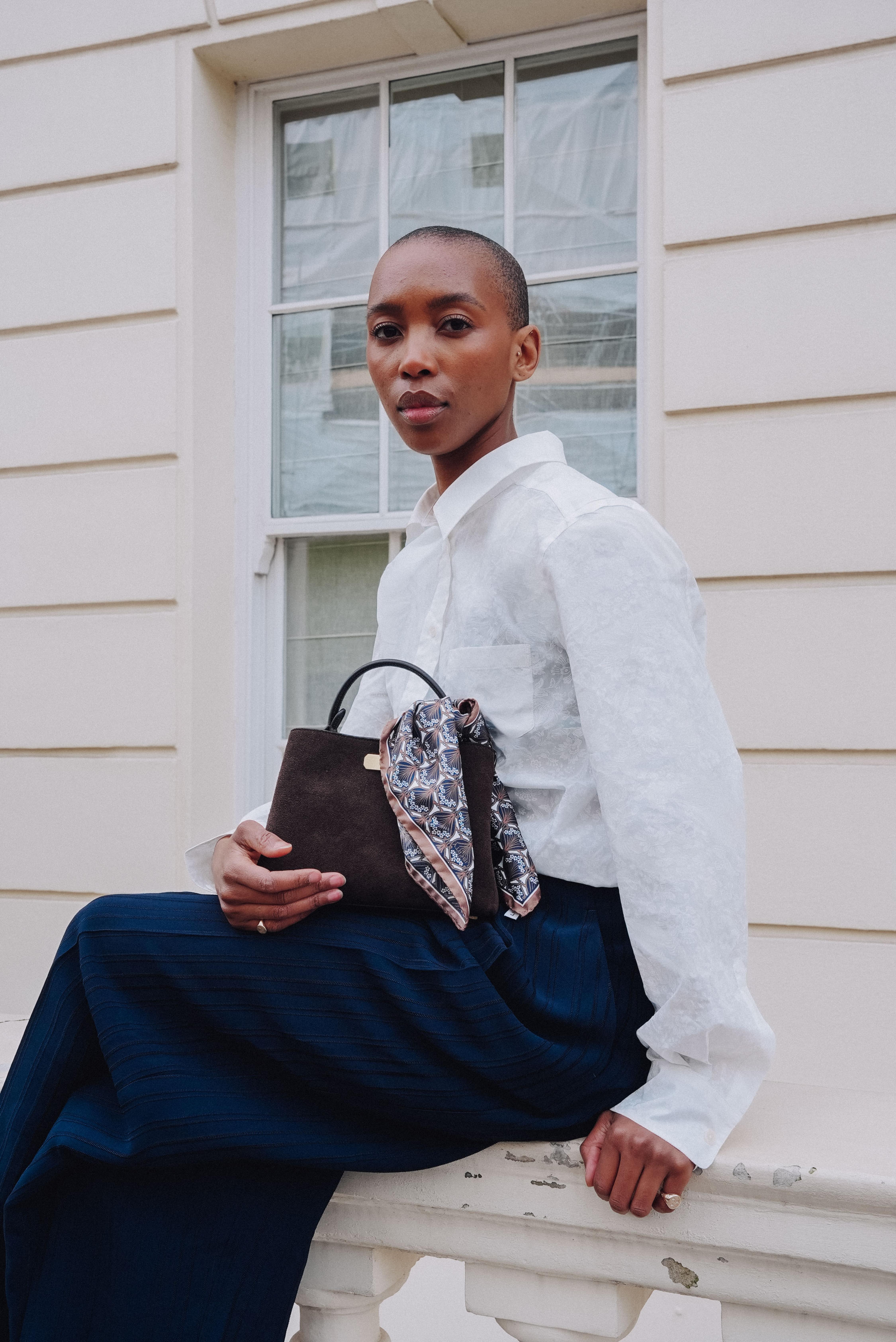 Image of Marisa holding a bag sitting on a window sill 