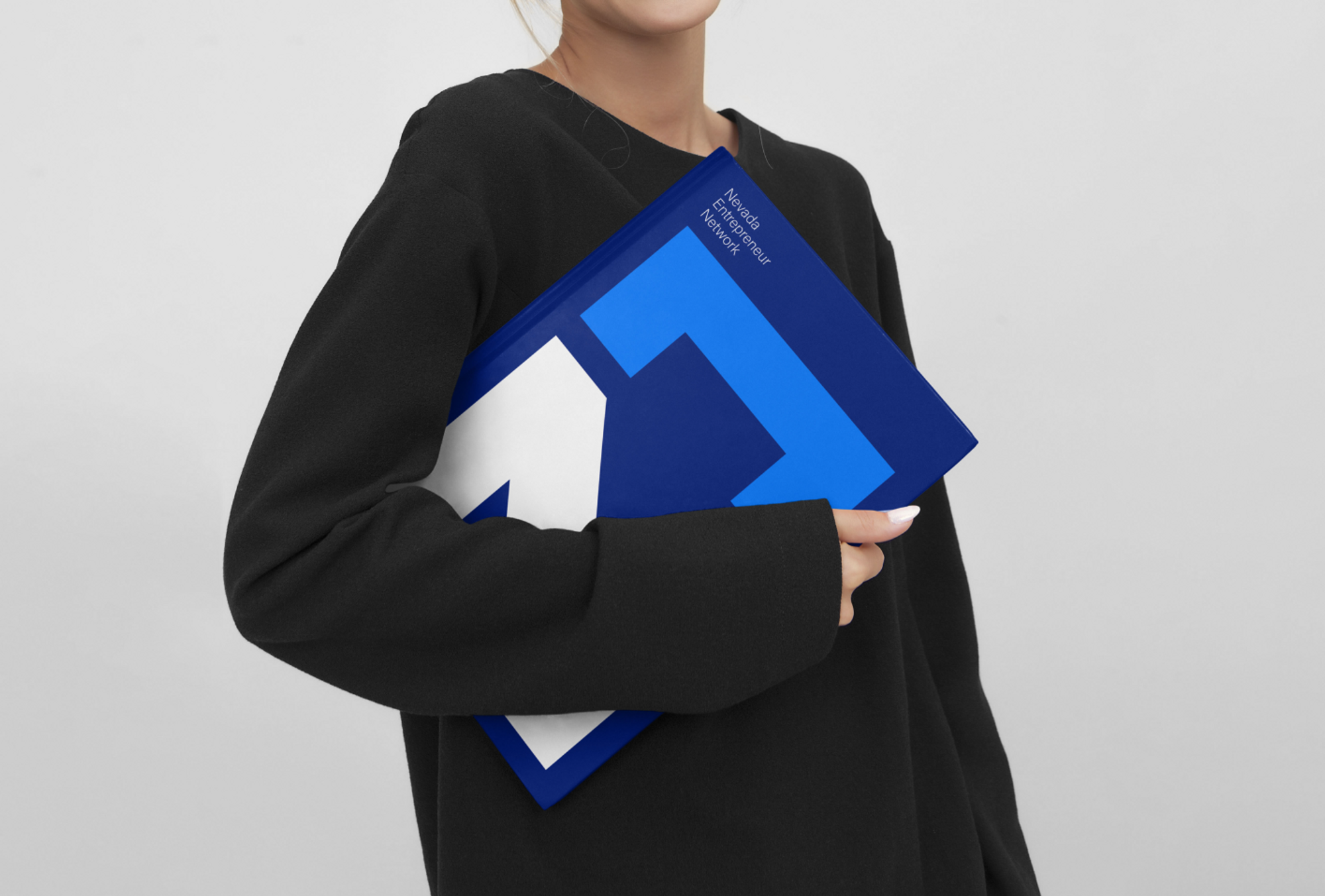 Woman holds book with Nevada Entrepreneur Network logo on it