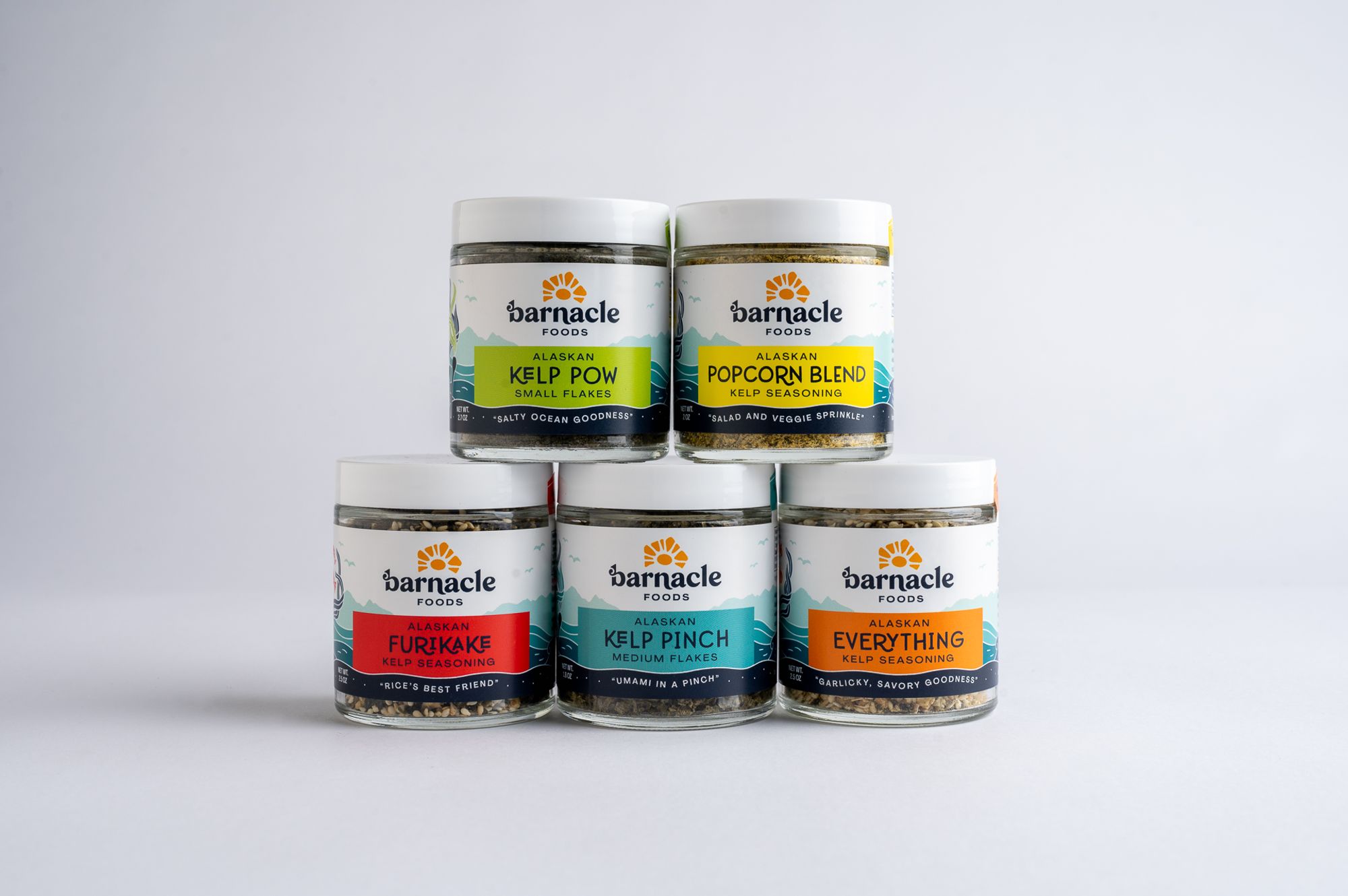 five colorful jars of food seasonings stacked on each other