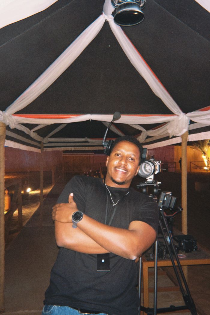 Sano beside a camera on set