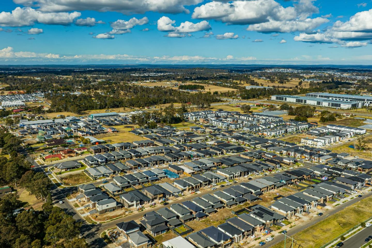 Aerial view of a large new subdivision of homes under construction, with open land around it.