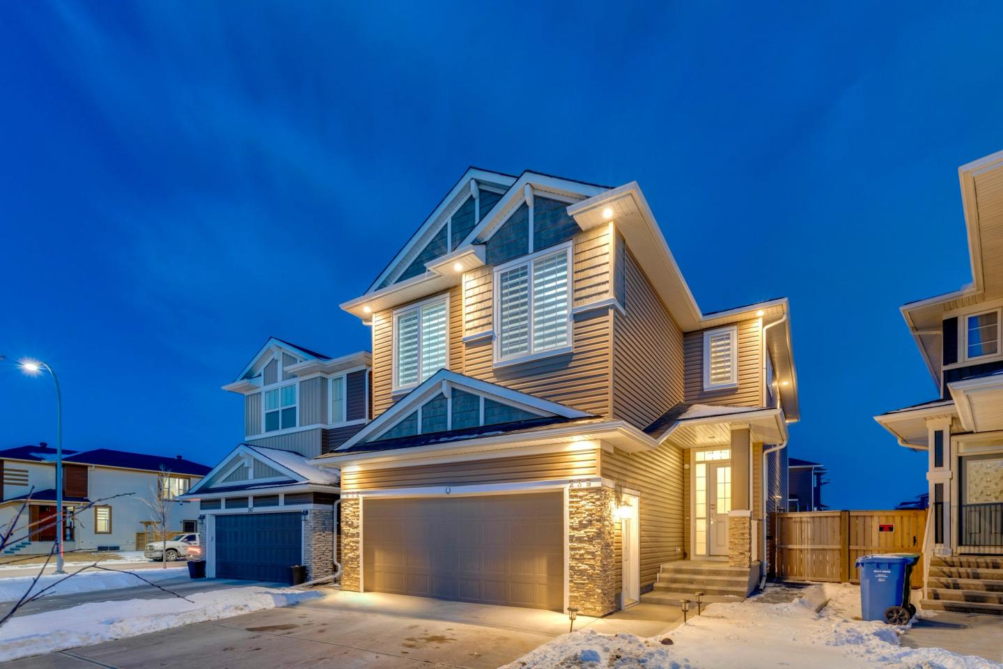 Newly built two-storey home in Calgary, Alberta, at dusk with snow on the driveway