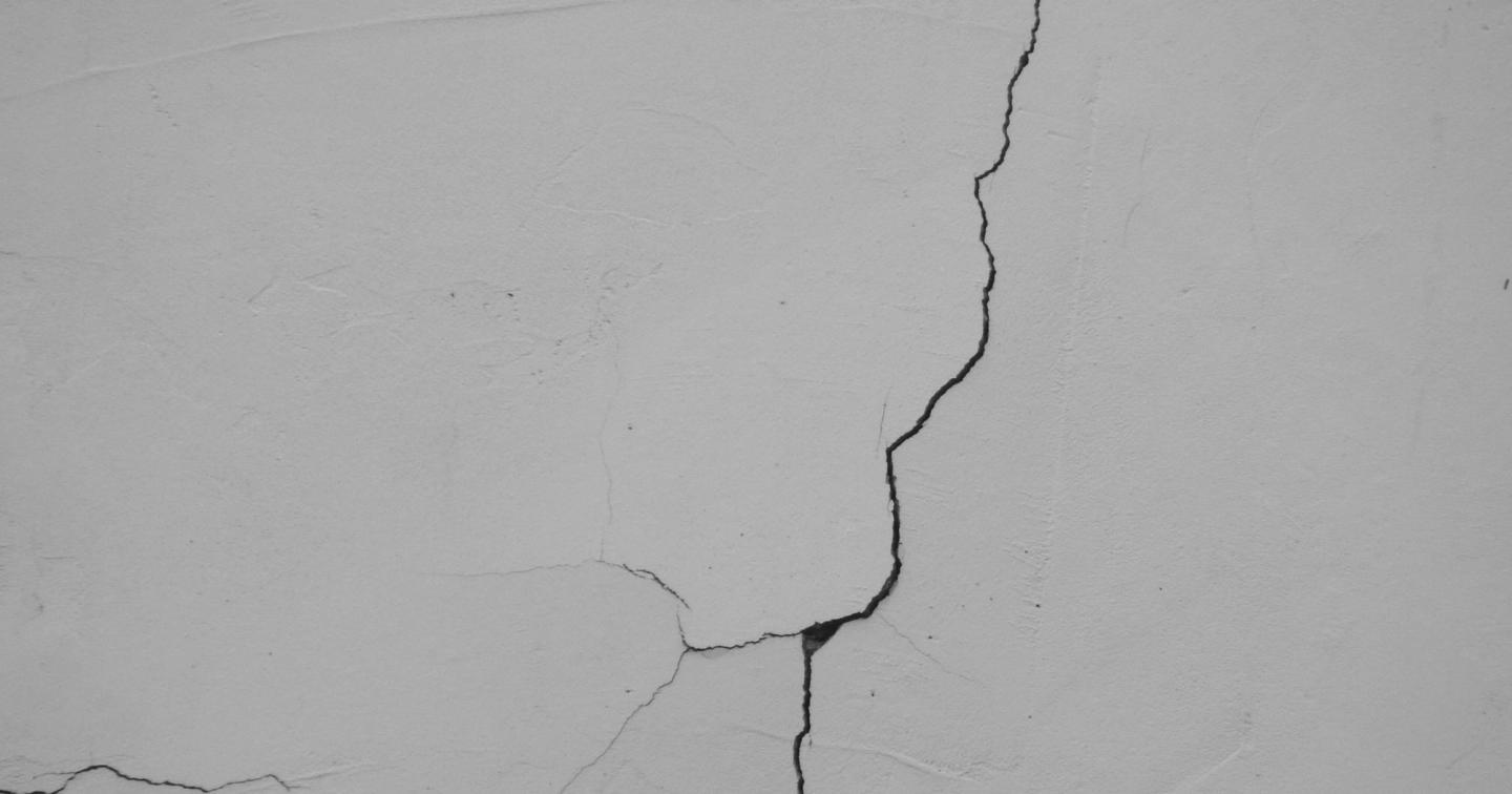 A long crack running across a finished white wall.