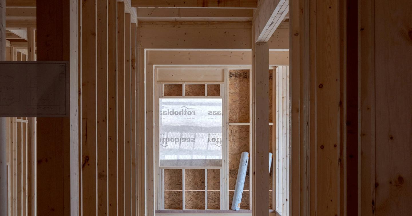 Wood-framed hallway in a building under construction, with studs and walls still open before drywall