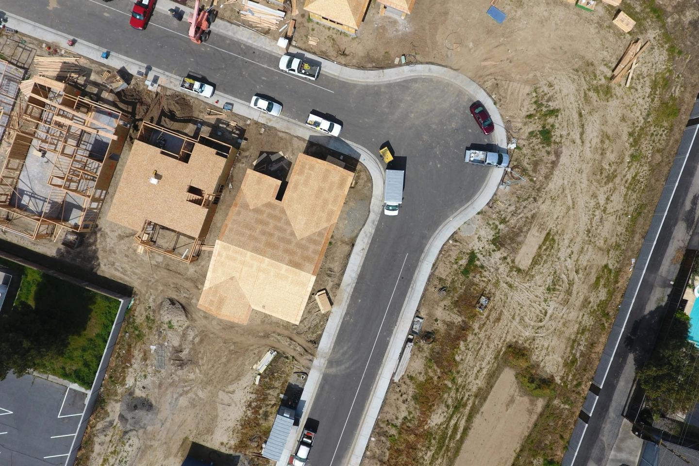 Aerial view of a new subdivision with houses at different stages of framing and roof sheathing