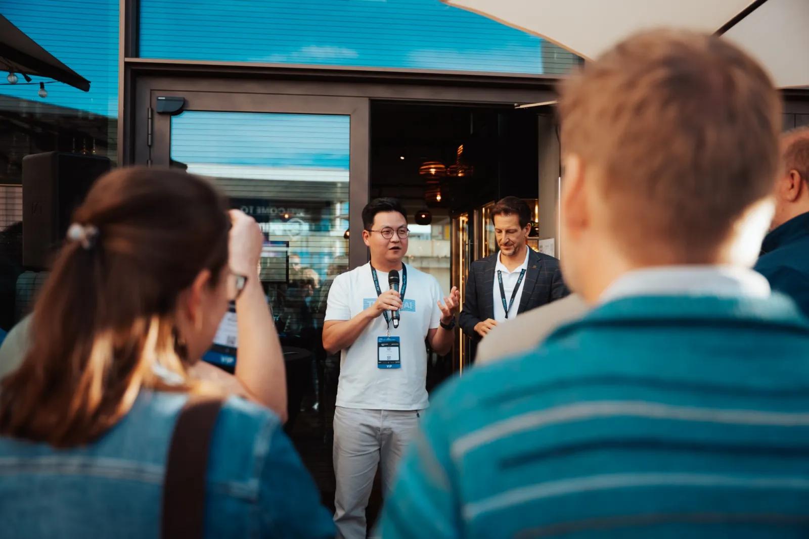 A host with a microphone welcoming guests on the restaurant terrace