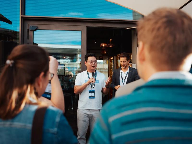 A host with a microphone welcoming guests on the restaurant terrace