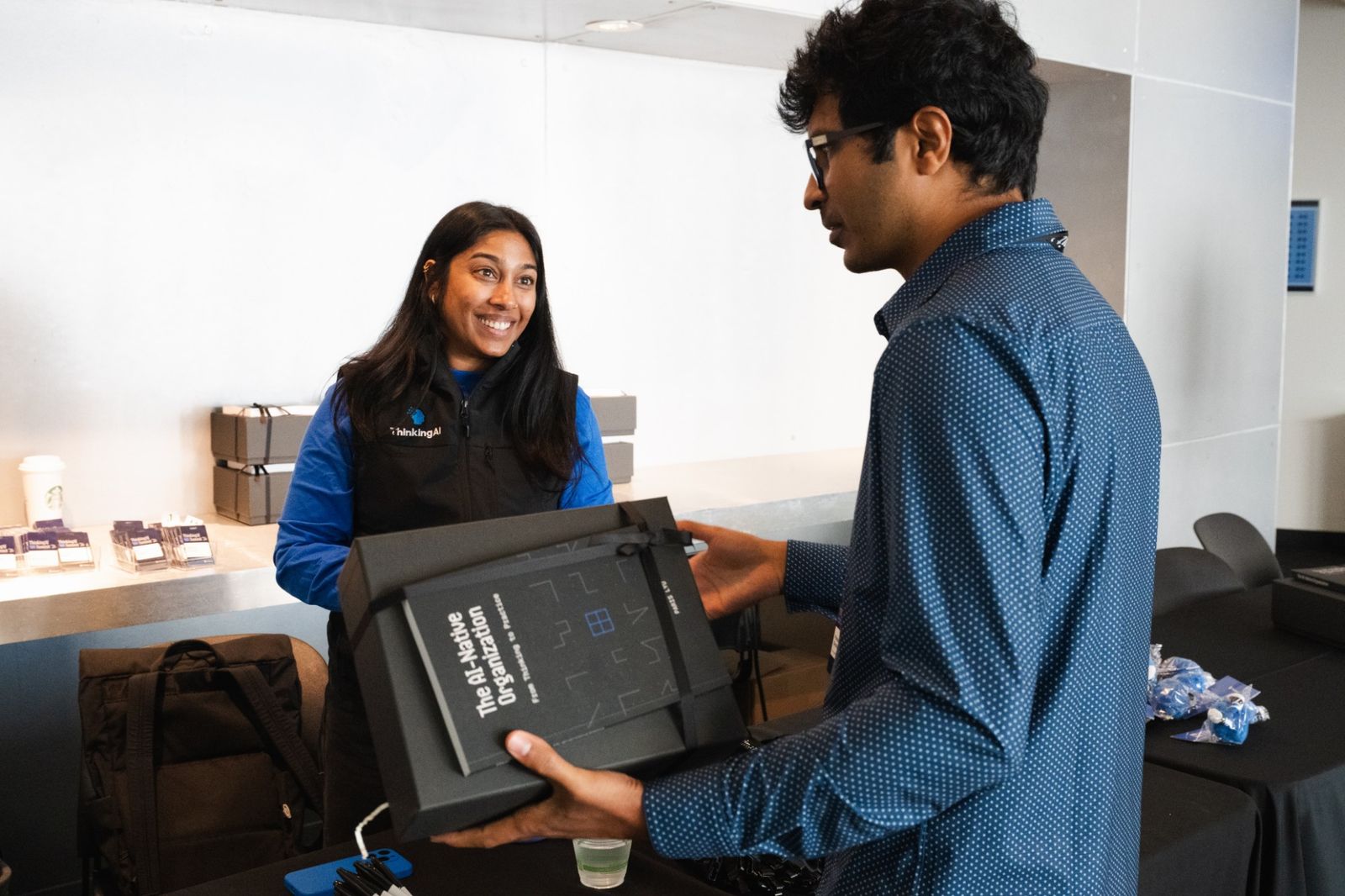 A ThinkingAI team member handing a boxed copy of the book to a guest