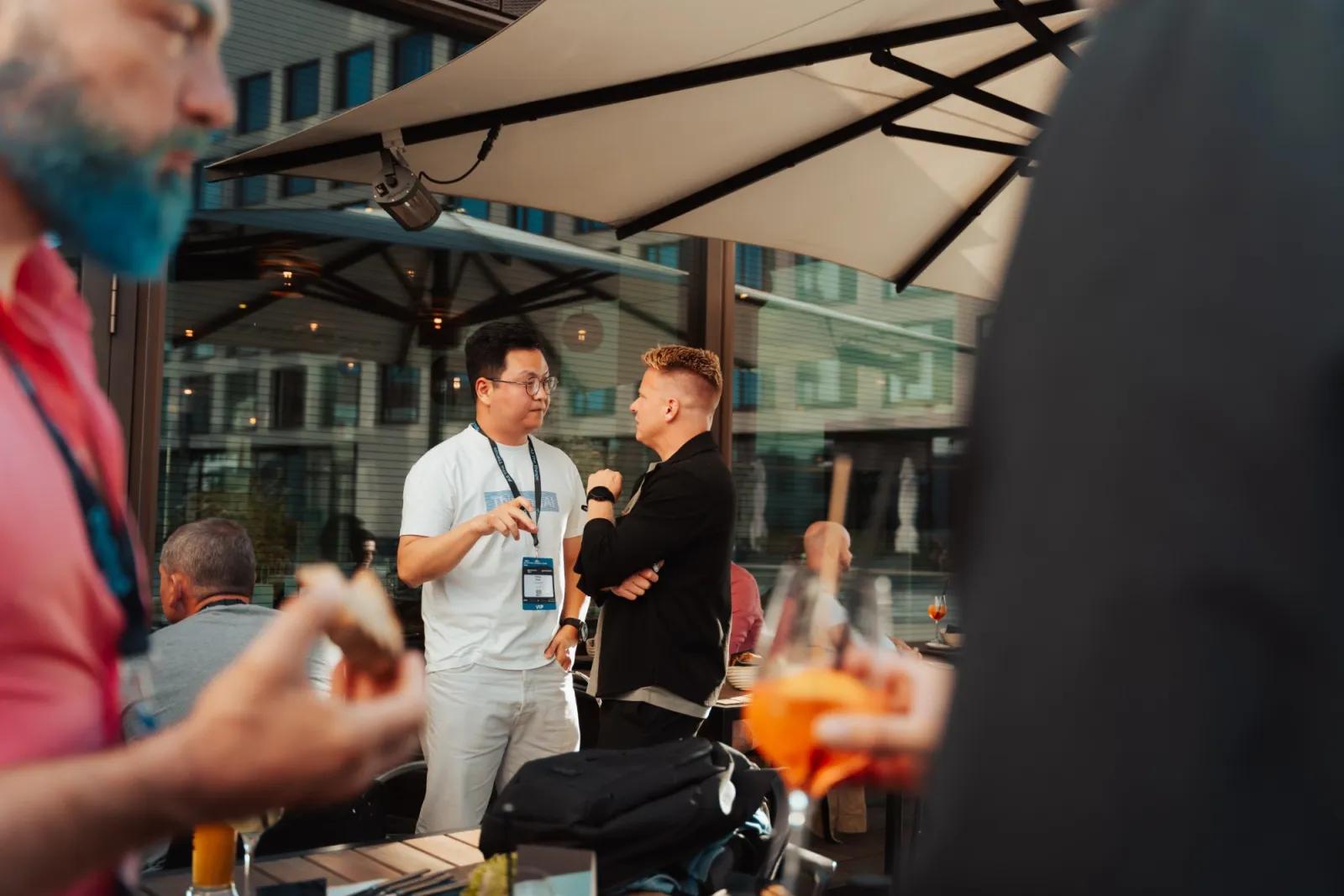 Two guests deep in conversation under the terrace umbrellas