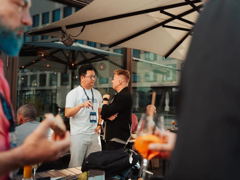 Two guests deep in conversation under the terrace umbrellas