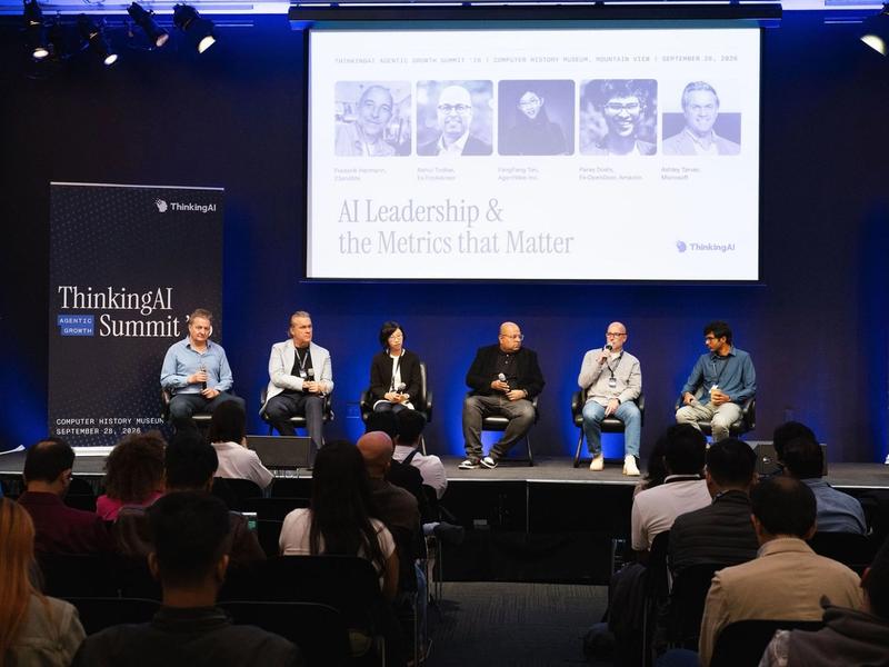 Five panelists and moderator Murray Newlands seated on stage