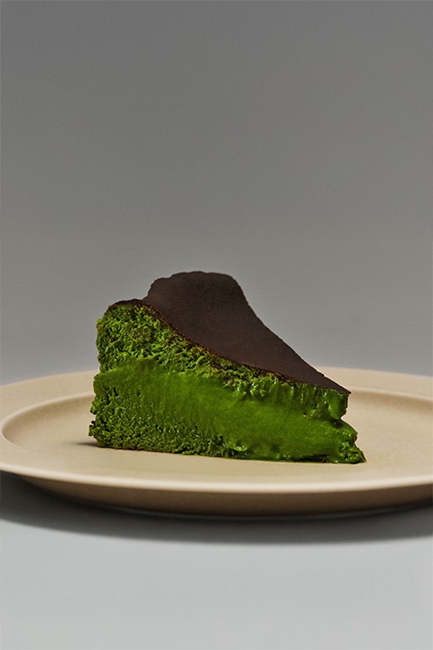 A plate of a slice of matcha basque cheesecake.