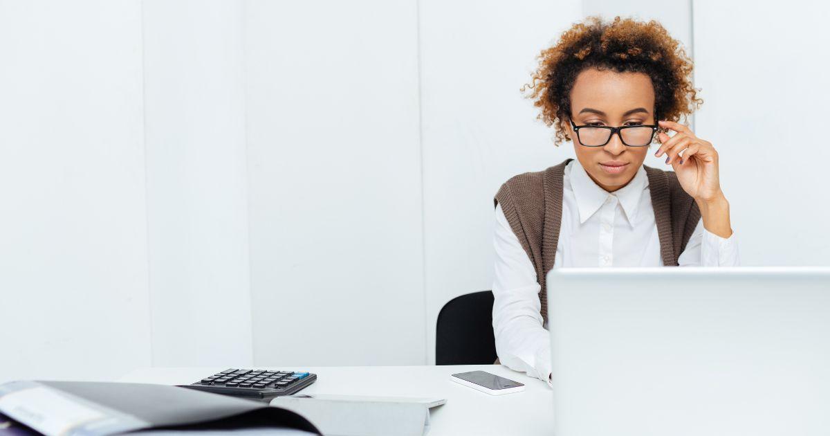 Mitarbeiterin arbeitet konzentriert am Laptop mit Taschenrechner – Symbolbild für Personalabrechnung im Personalmanagement