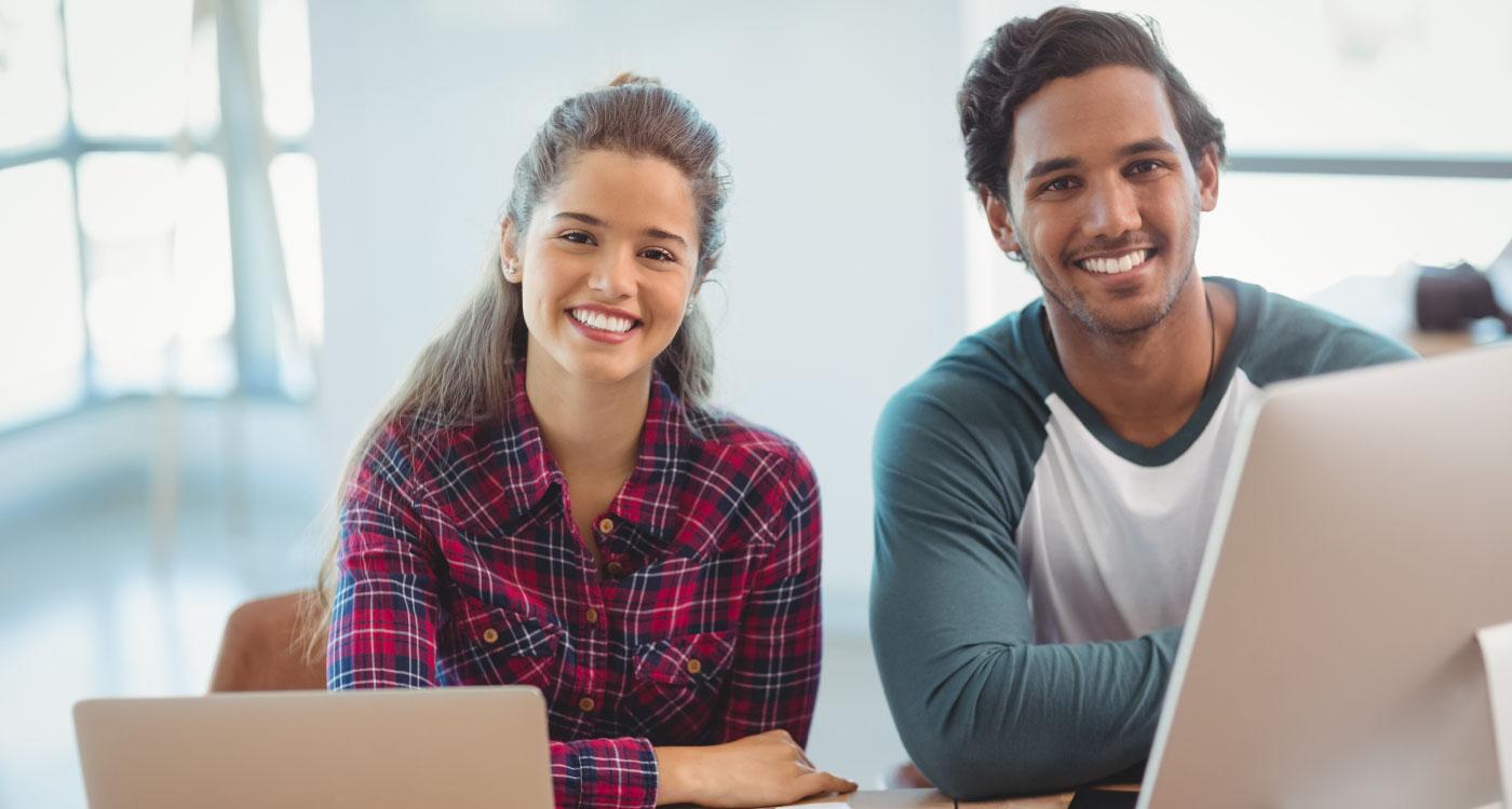 Zwei lächelnde Kollegen am Computer im Büro – Symbolbild für den Job Profile Builder in SuccessFactors