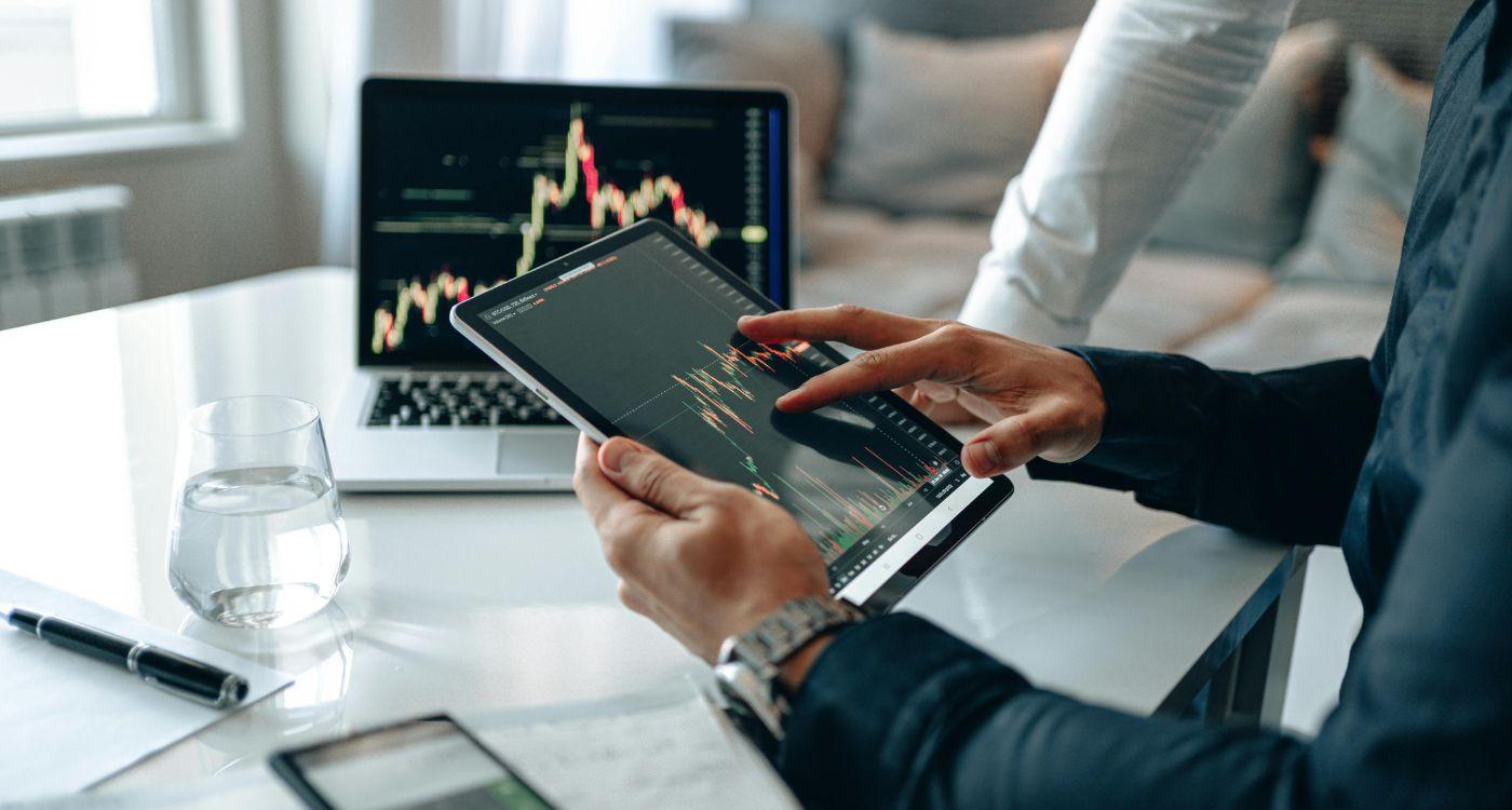 Person analysiert Finanzdiagramme auf Tablet und Laptop – Symbolbild für generative KI in der SAP Analytics Cloud