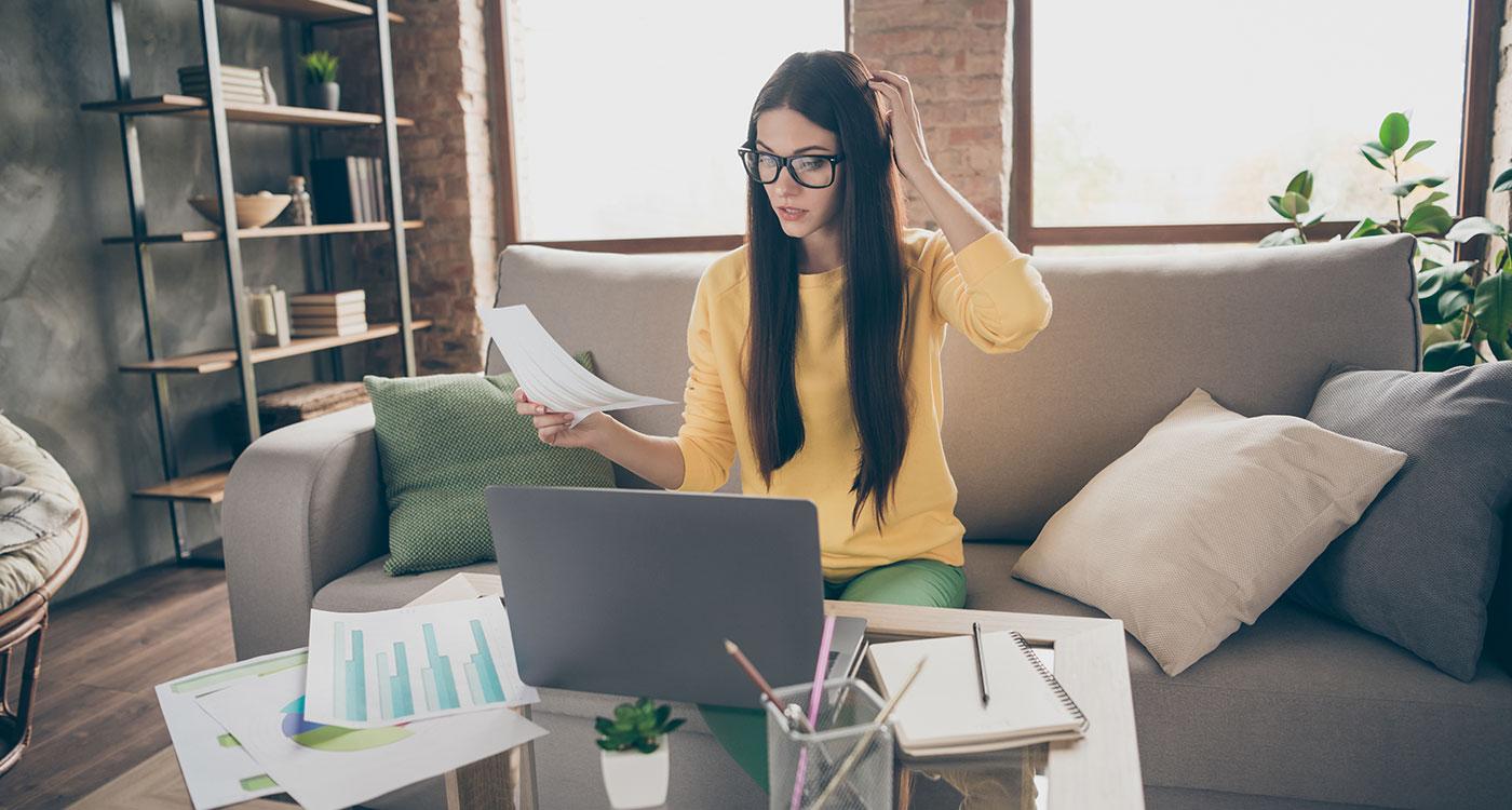 Nachdenkliche Frau prüft Unterlagen am Laptop im Homeoffice – Symbolbild für häufige Fragen zum Payroll Outsourcing