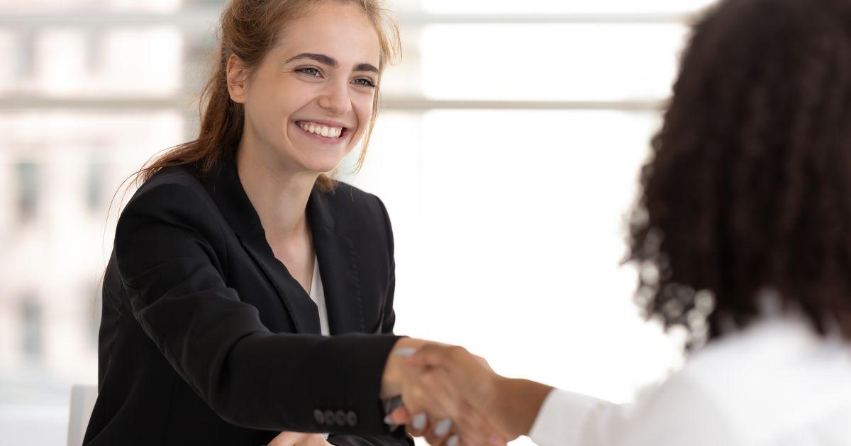 Lächelnde Mitarbeiterin gibt die Hand im Büro – Symbolbild für positive Erfahrungen im HR Service Delivery