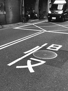 Photo of a road marking with a Chinese character mixed with a sewer hatch. 