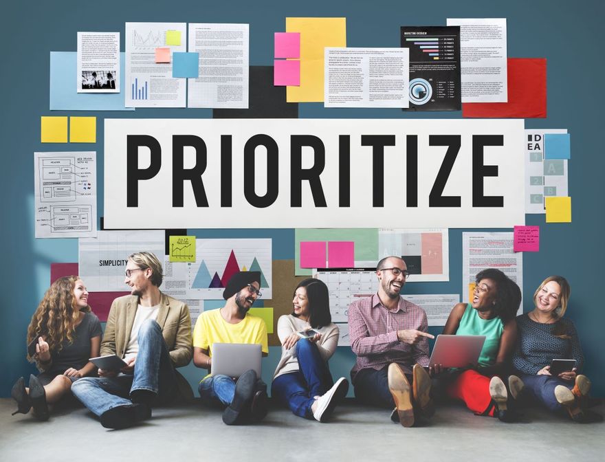 Young work team sitting behind a wall that says "prioritize"