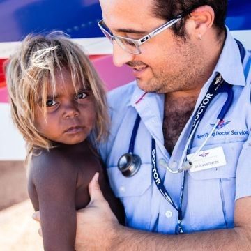 Image of doctor from Royal Flying Doctor Service holding Indigenous child 