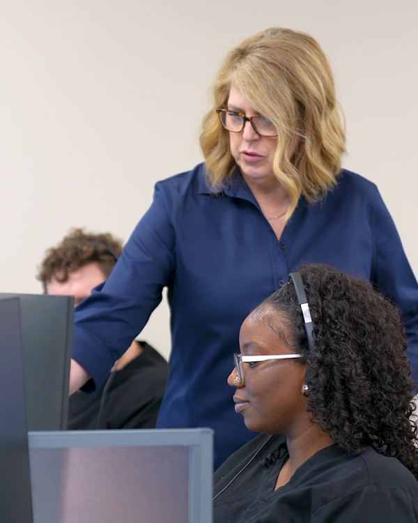 An Auxira pod lead checking in with a nurse practitioner at her workstation