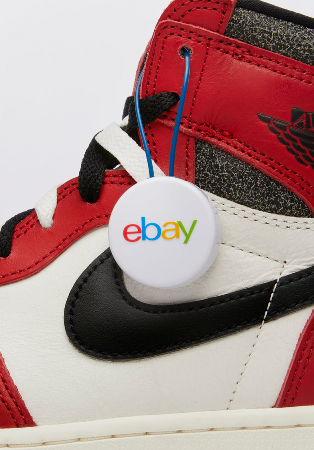 Close-up of a red, black, and off-white Air Jordan 1 sneaker with an eBay authenticity guarantee tag attached.