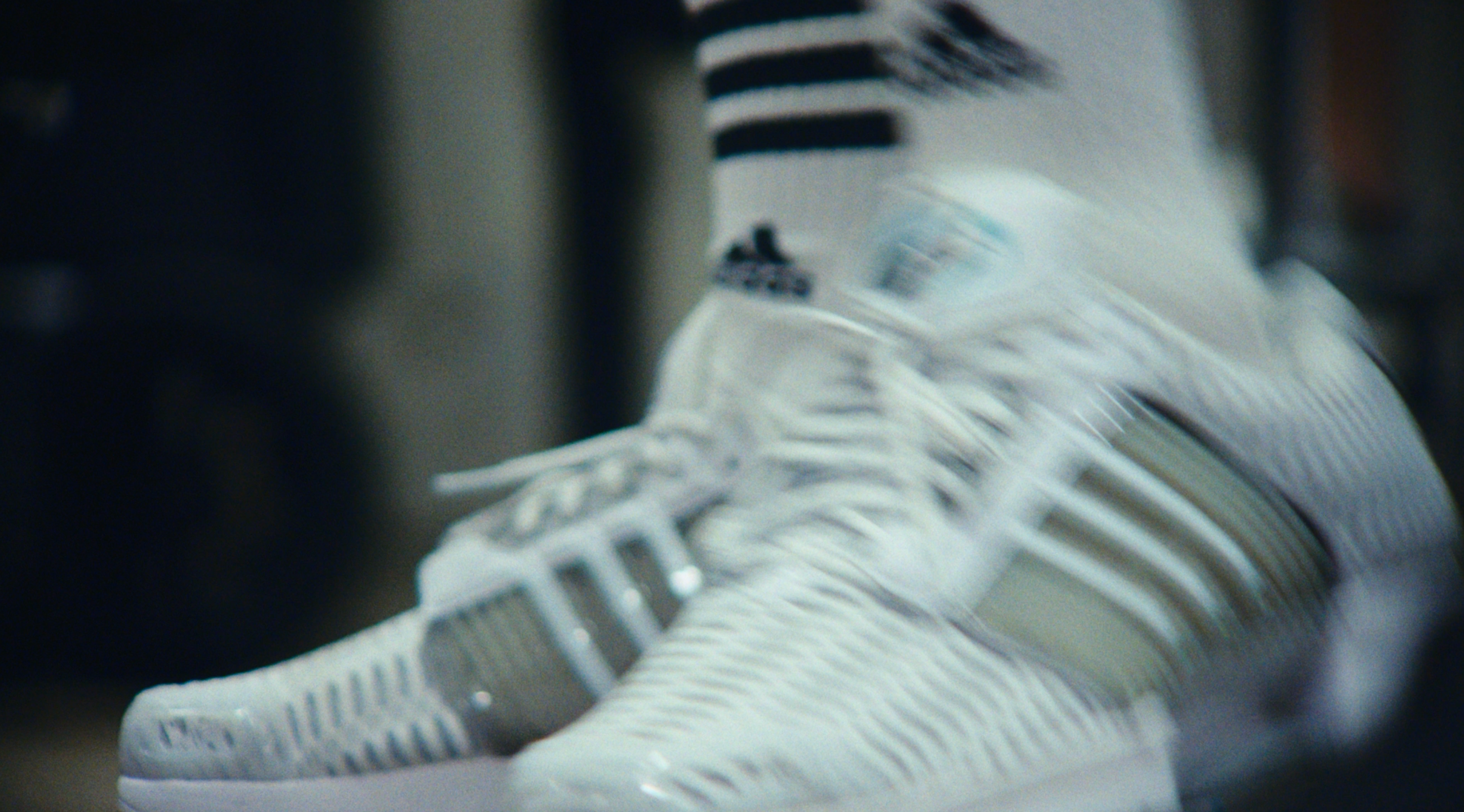 Motion-blurred close-up of white adidas CLIMACOOL sneakers worn with white socks and a black-striped sock band