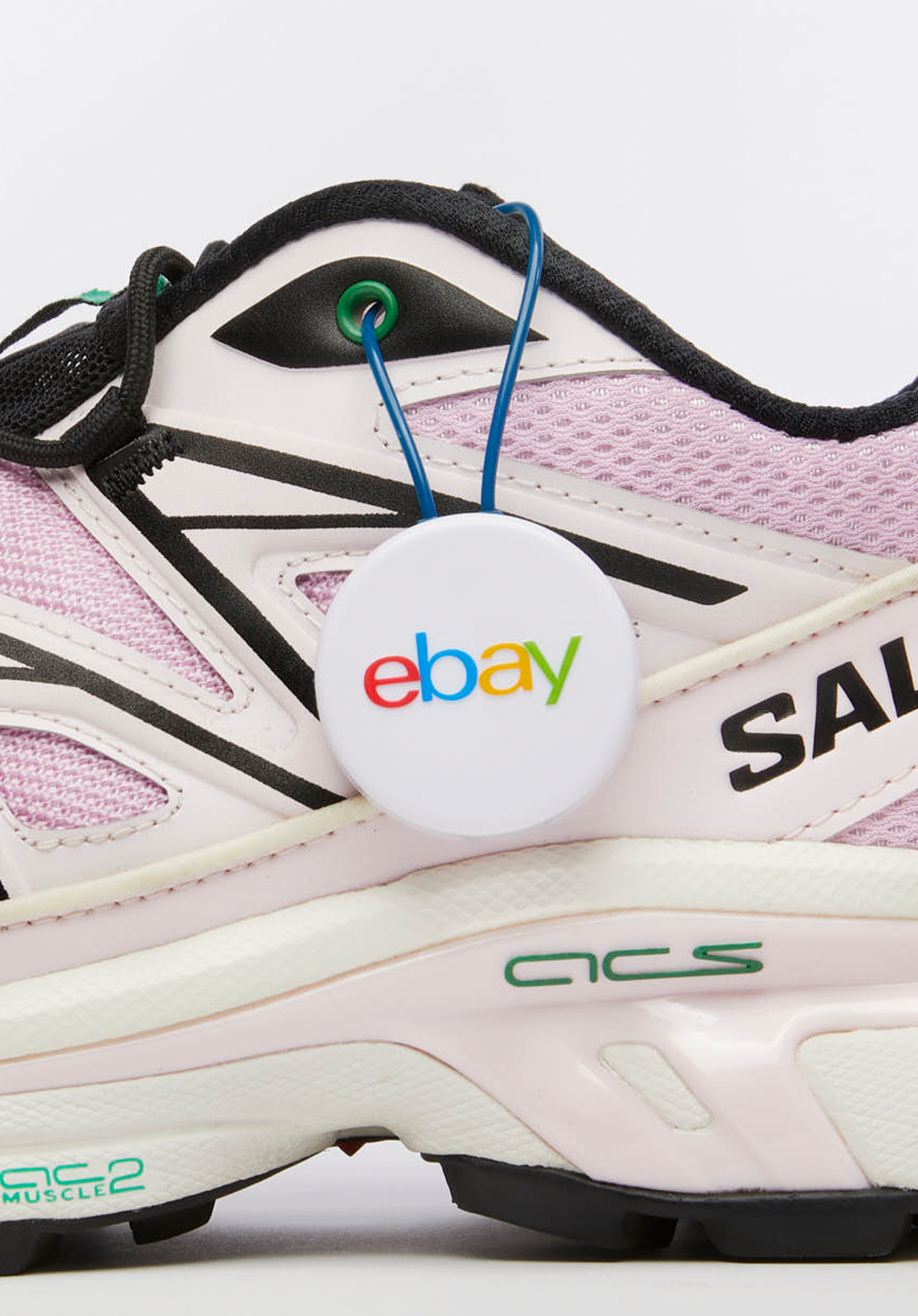 Close-up of a pink and white Salomon shoe with an eBay authenticity tag.