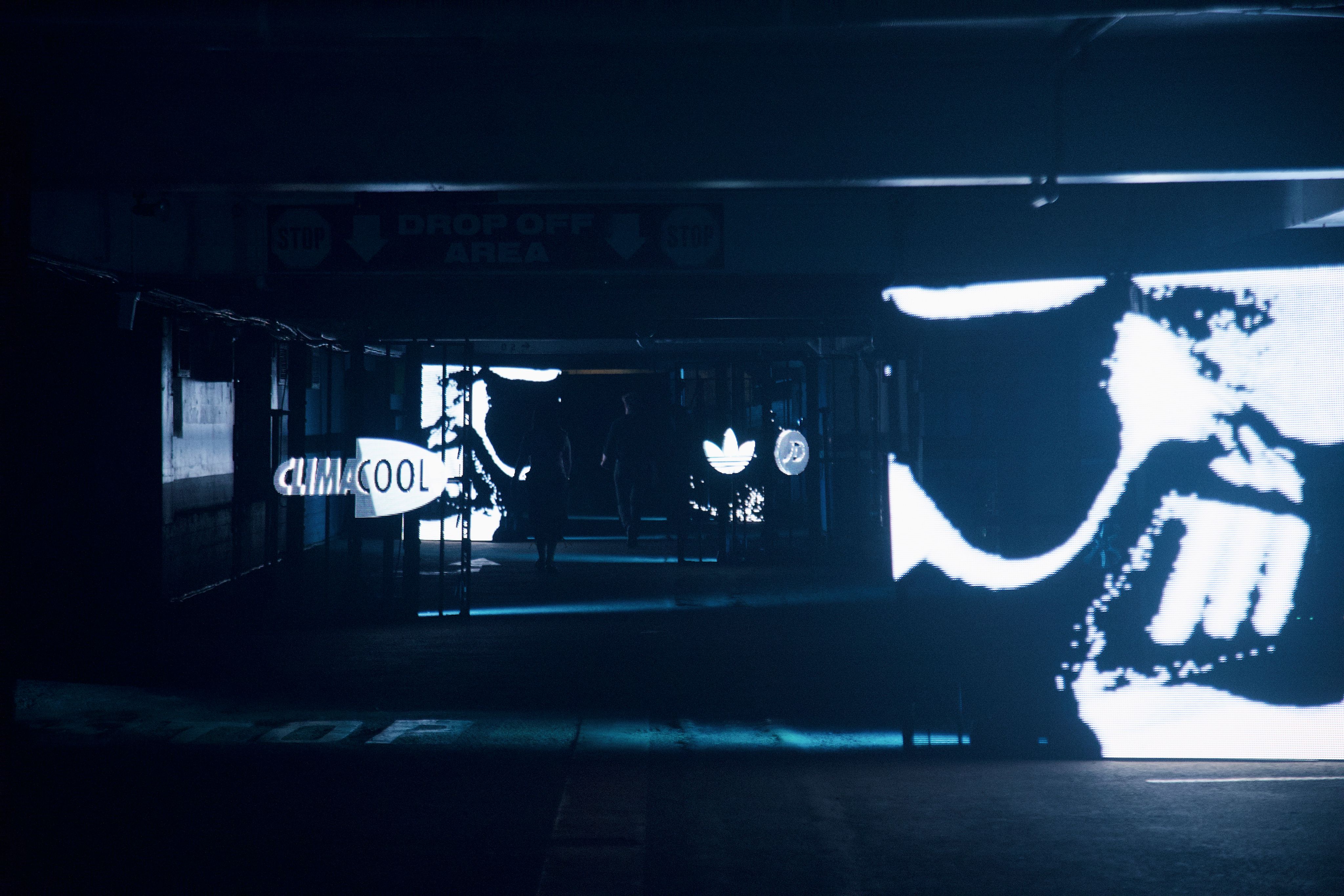 Cinematic low-light shot of the CLIMACOOL event entrance at Wynyard Station — a Drop Off Area sign, an adidas trefoil and a large illuminated CLIMACOOL logo glowing in the dark