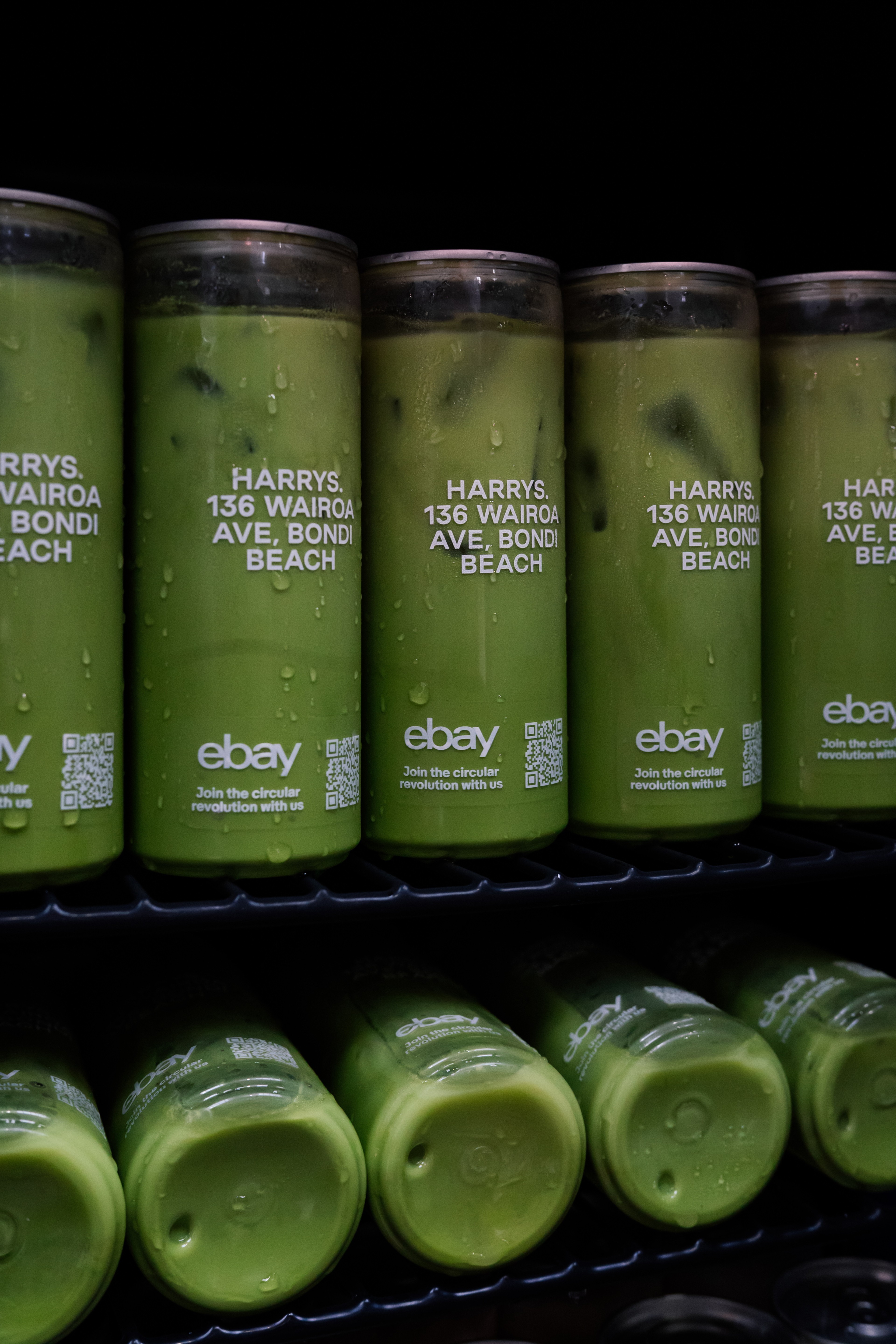 Shelves of green glass bottles used as set decor inside the Pre-Loved Lounge