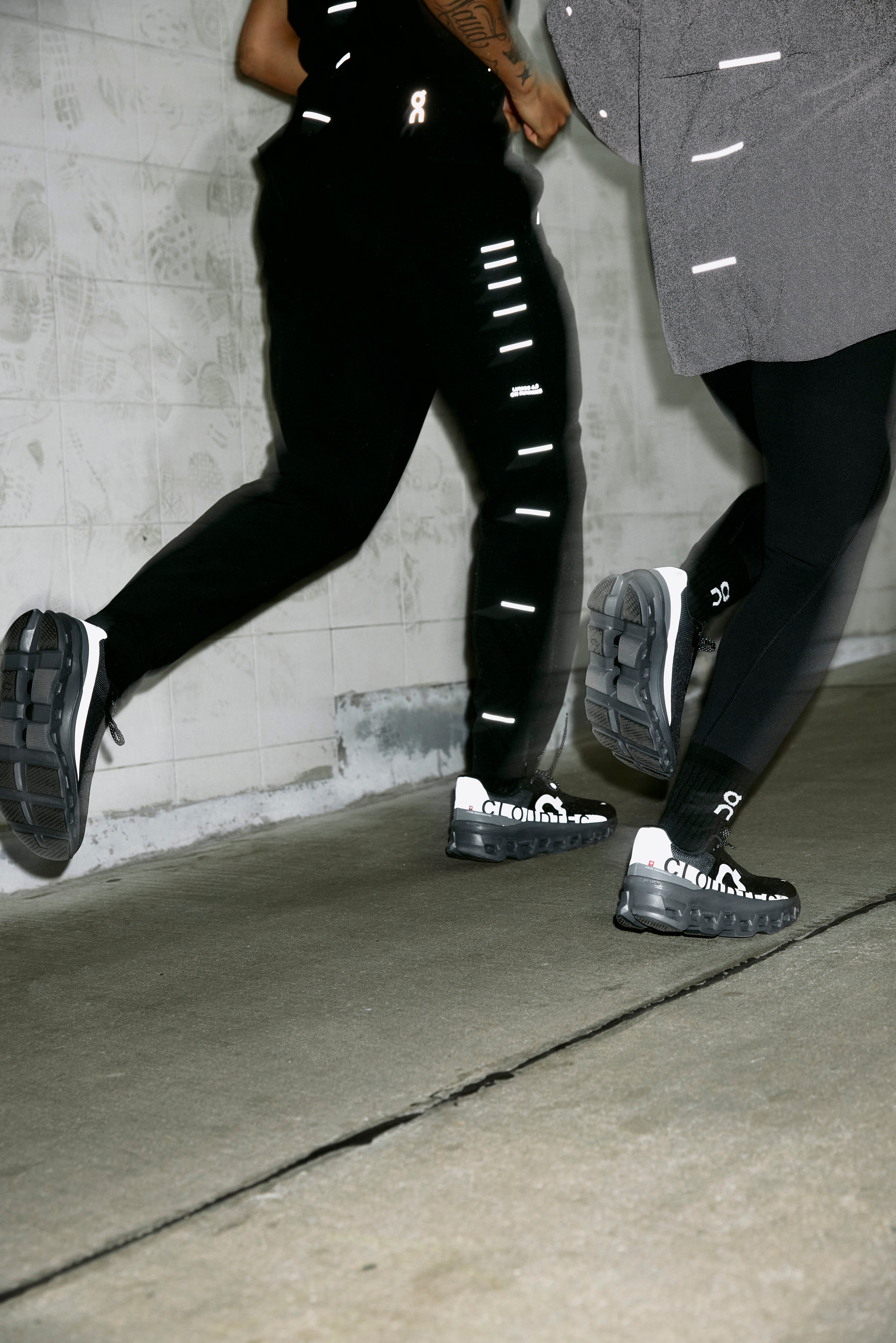 Runner mid-stride in black Lumos capsule leggings and On shoes on an urban street