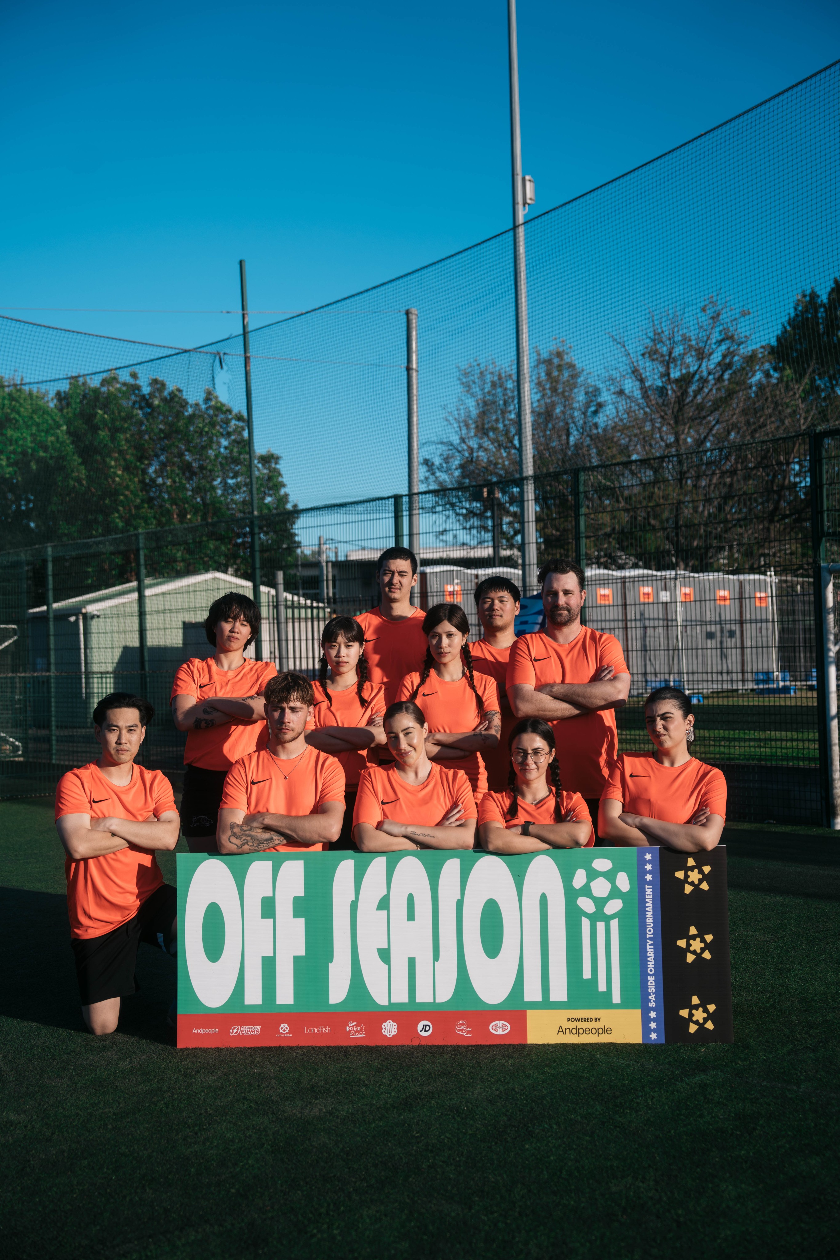 Off Season team group photo posing with a yellow OFF SEASON tournament banner on a football pitch
