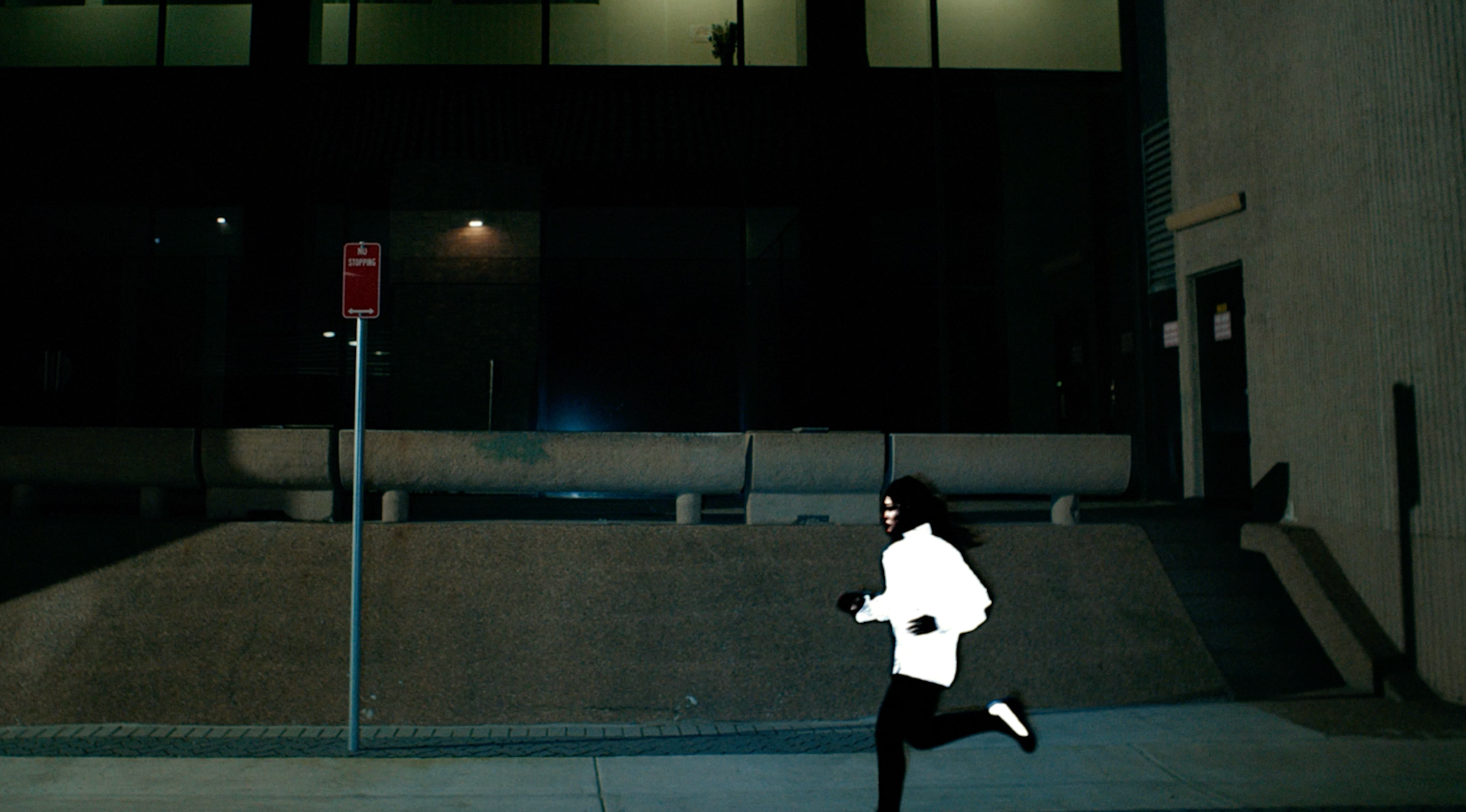 Silhouette of a runner passing a reflective On logo at night