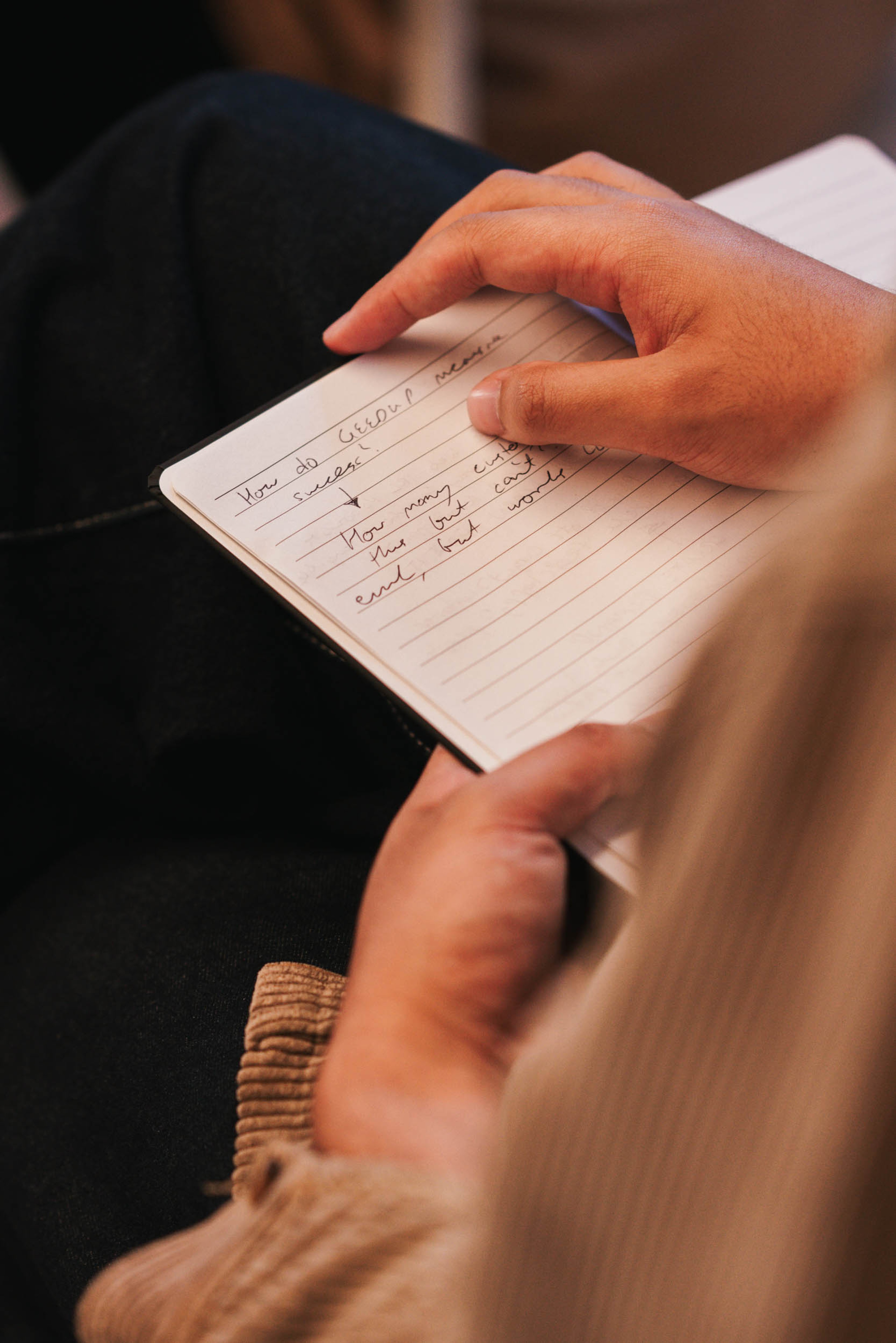 Hands hold an open notebook with handwritten notes.