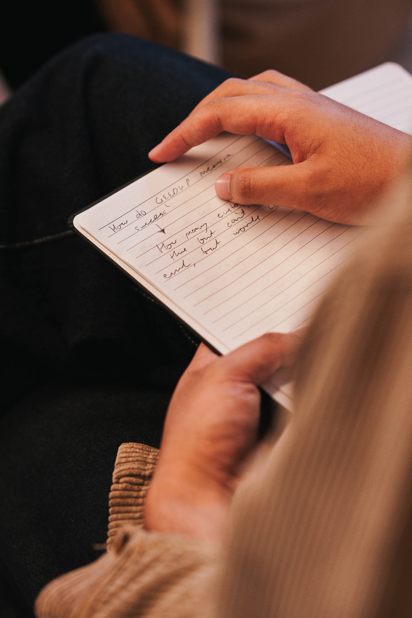 Hands hold an open notebook with handwritten notes.