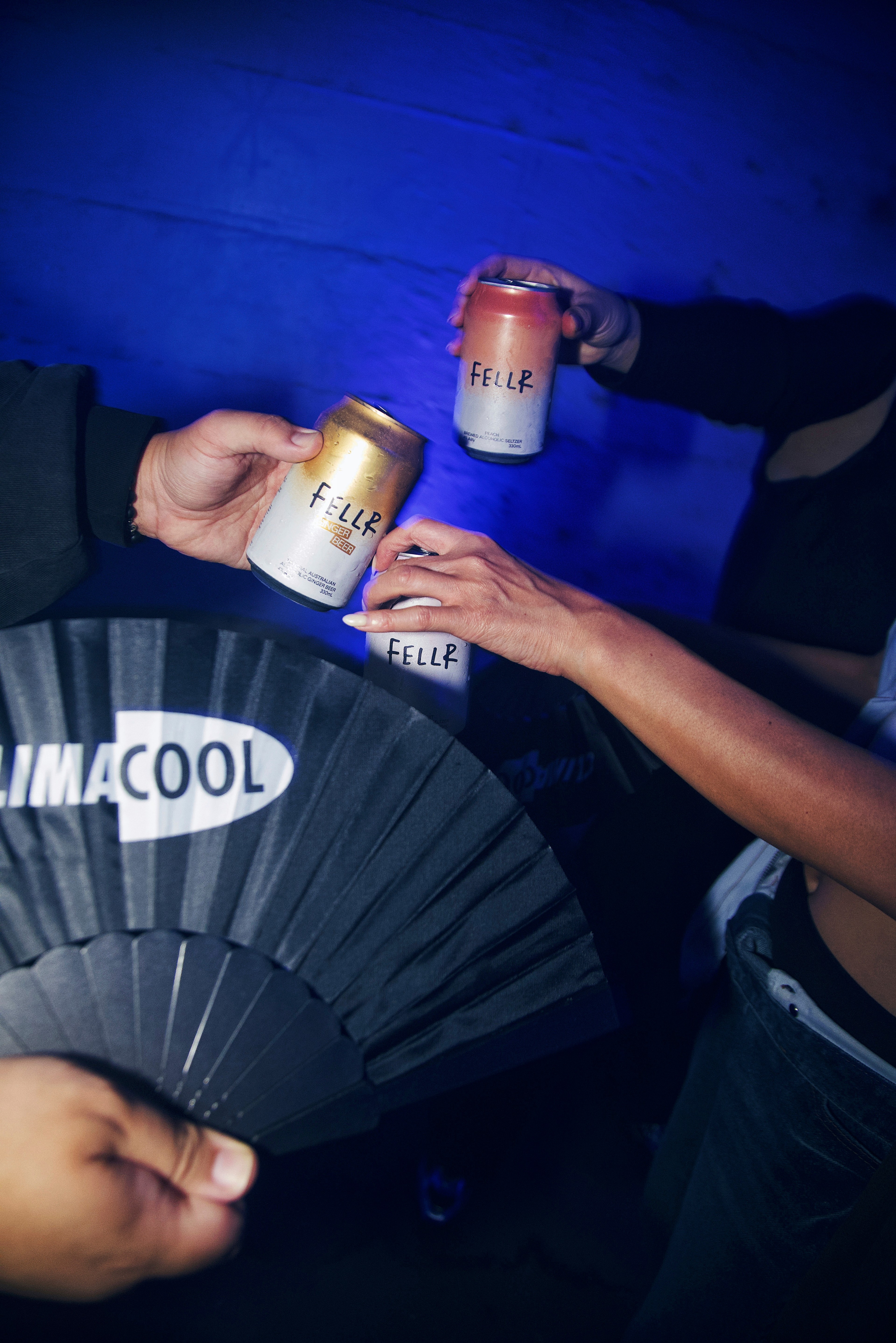 Attendees toasting with Fellr cans while holding a CLIMACOOL-branded folding fan at the Wynyard Tunnels event