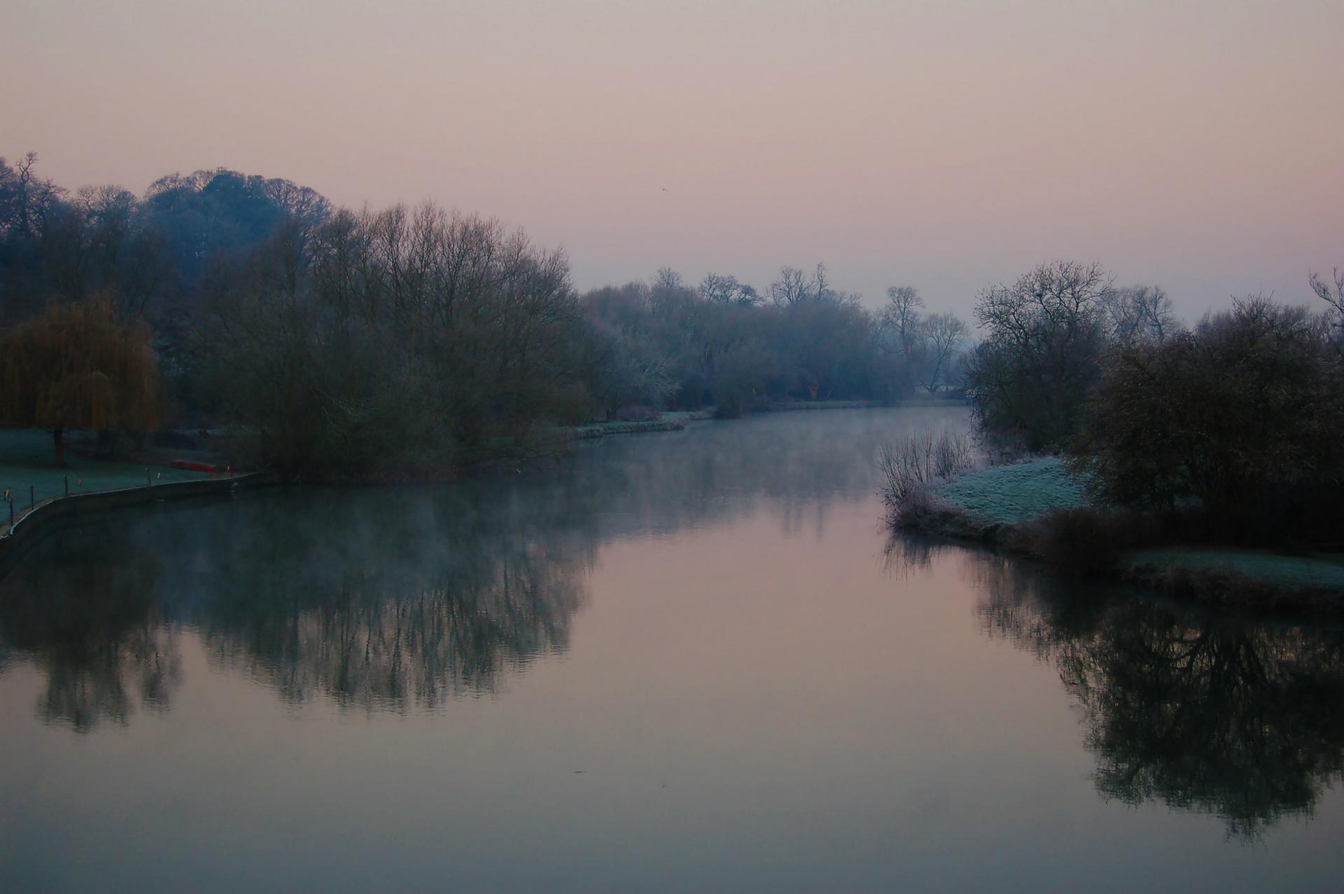 The River Thames in Berkshire on a frosty, misty morning, with bare trees reflected in the still water.