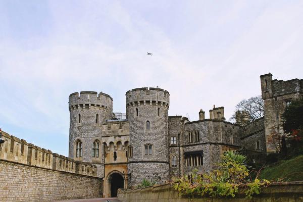 The twin drum towers of the Norman Gate at Windsor Castle under a pale sky.
