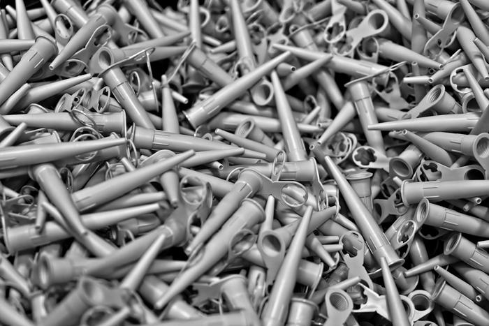 Black-and-white close-up of a pile of plastic sealant cartridge nozzles.