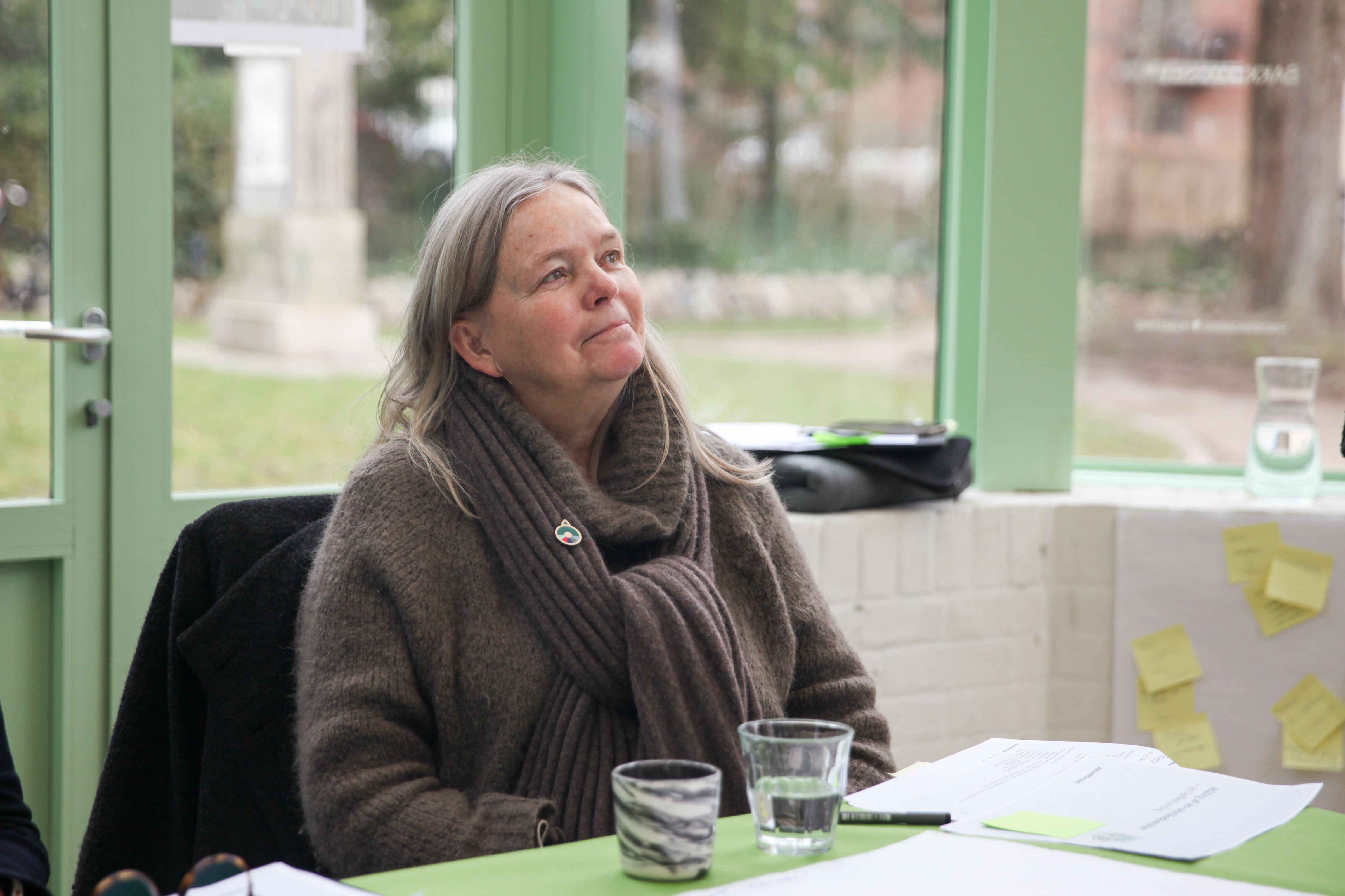 Kvinde sidder i cafe og lytter opmærksomt til en person uden for billedet.