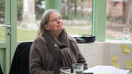 Kvinde sidder i cafe og lytter opmærksomt til en person uden for billedet.