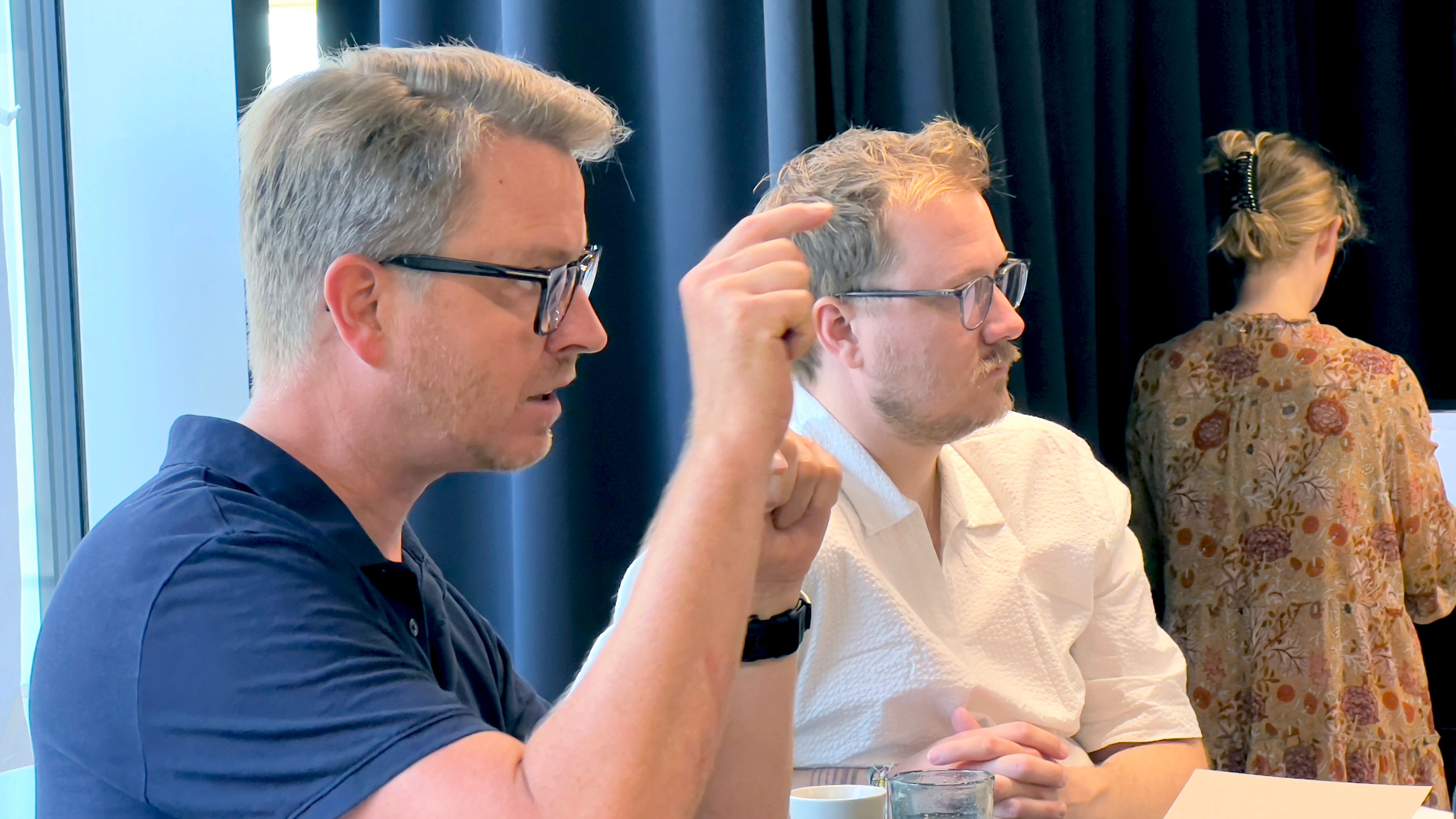 To mænd ved bord. Den ene taler