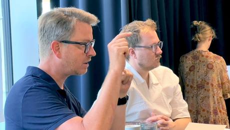 To mænd ved bord. Den ene taler