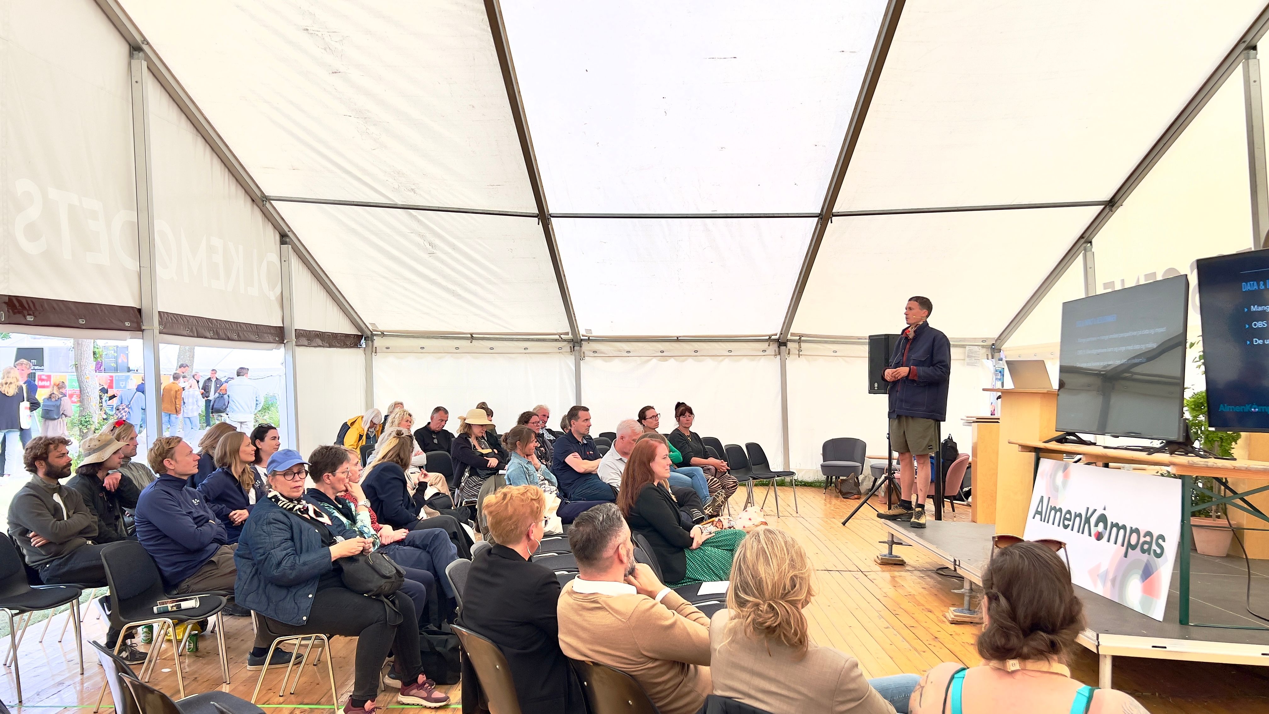 Stort, lyst debattelt med mand på scenen og ca. 25 tilhørere