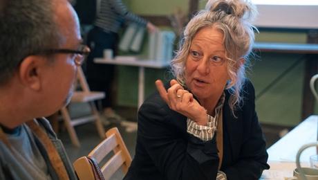 Kvinde og mand sidder i drøftelse ved bord