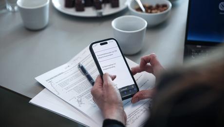 Closeup af mobiltelefon i hænderne på mødedeltager