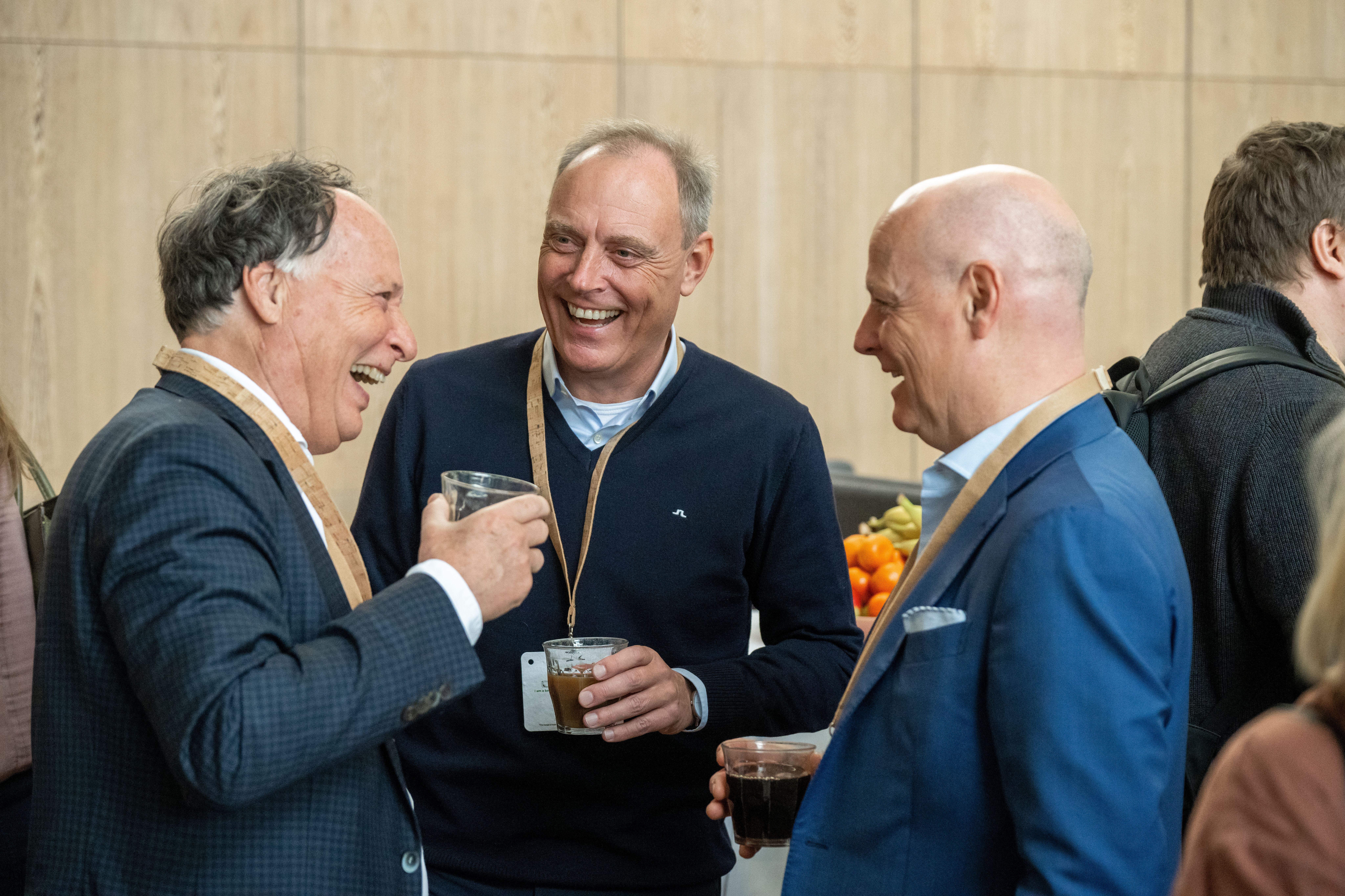 Tre direktører griner og drikker kaffe til AlmenKompas-kickoff